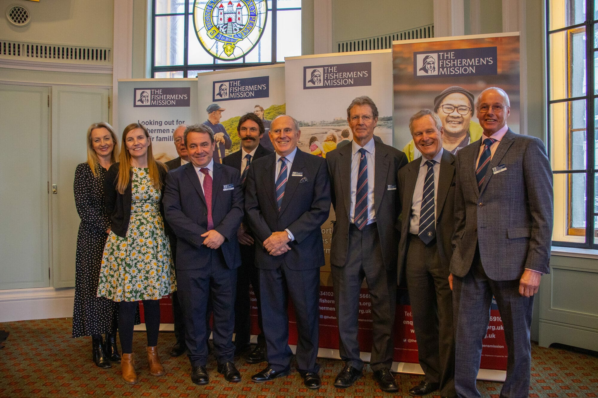 A group of Trustees standing in front of pop up banners.